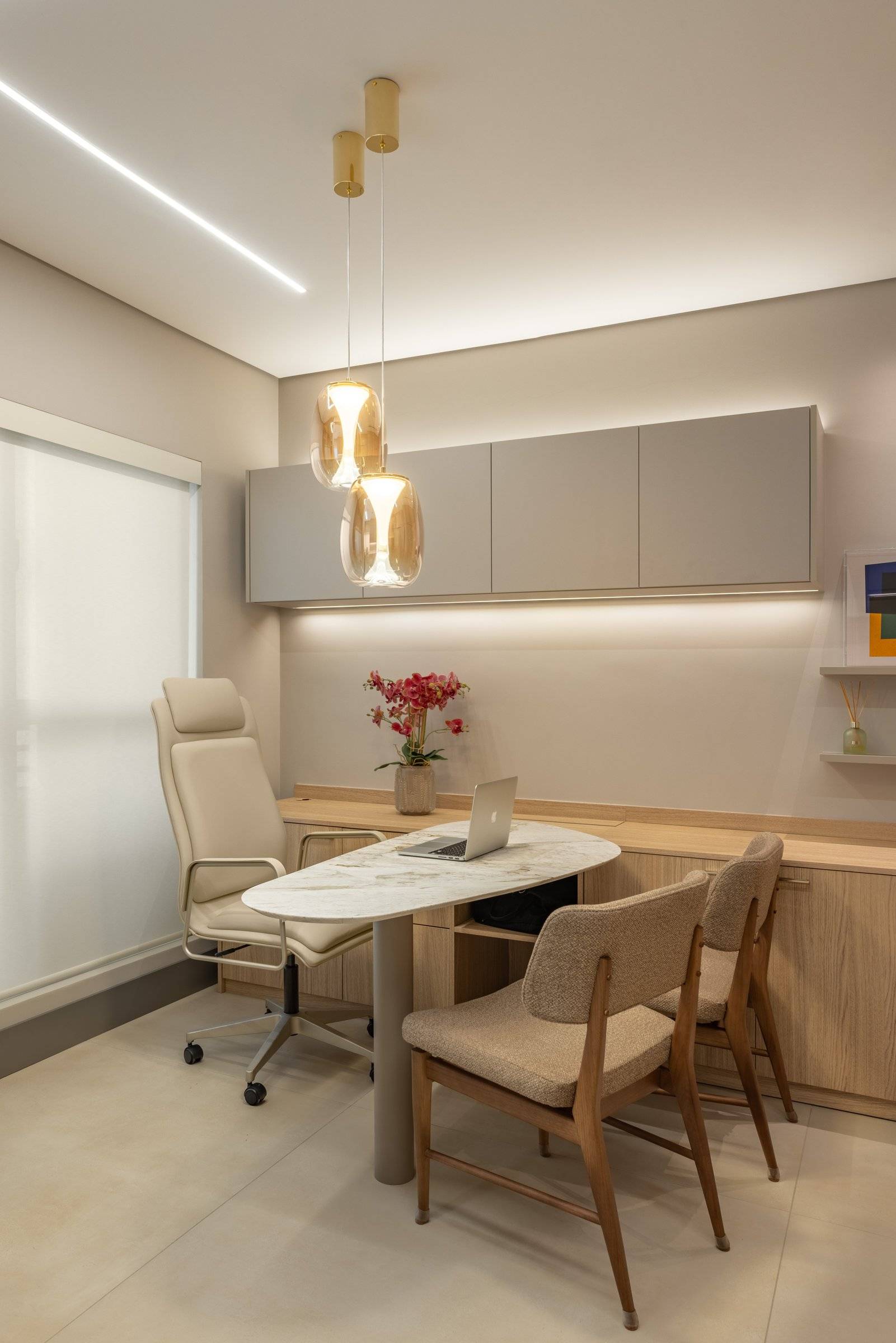 Consultório com mesa oval e janela com persiana clara