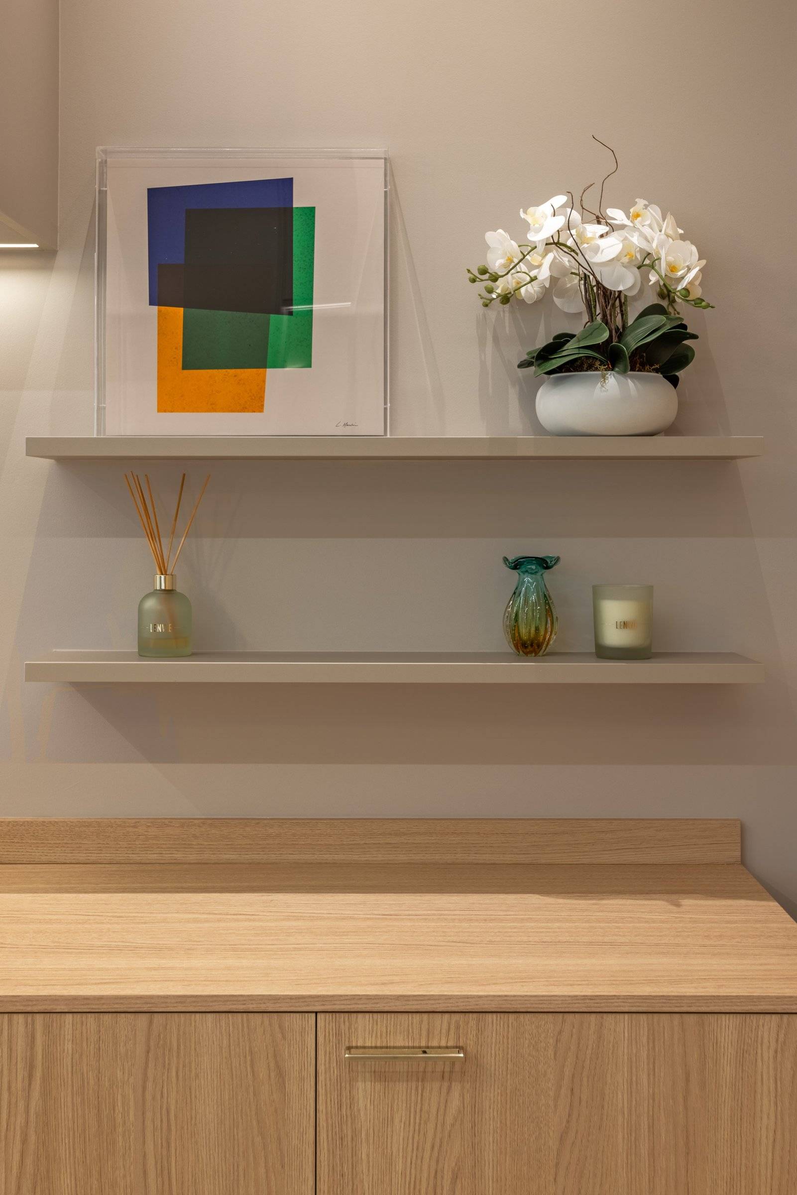 Prateleiras com quadro colorido, orquídea e objetos