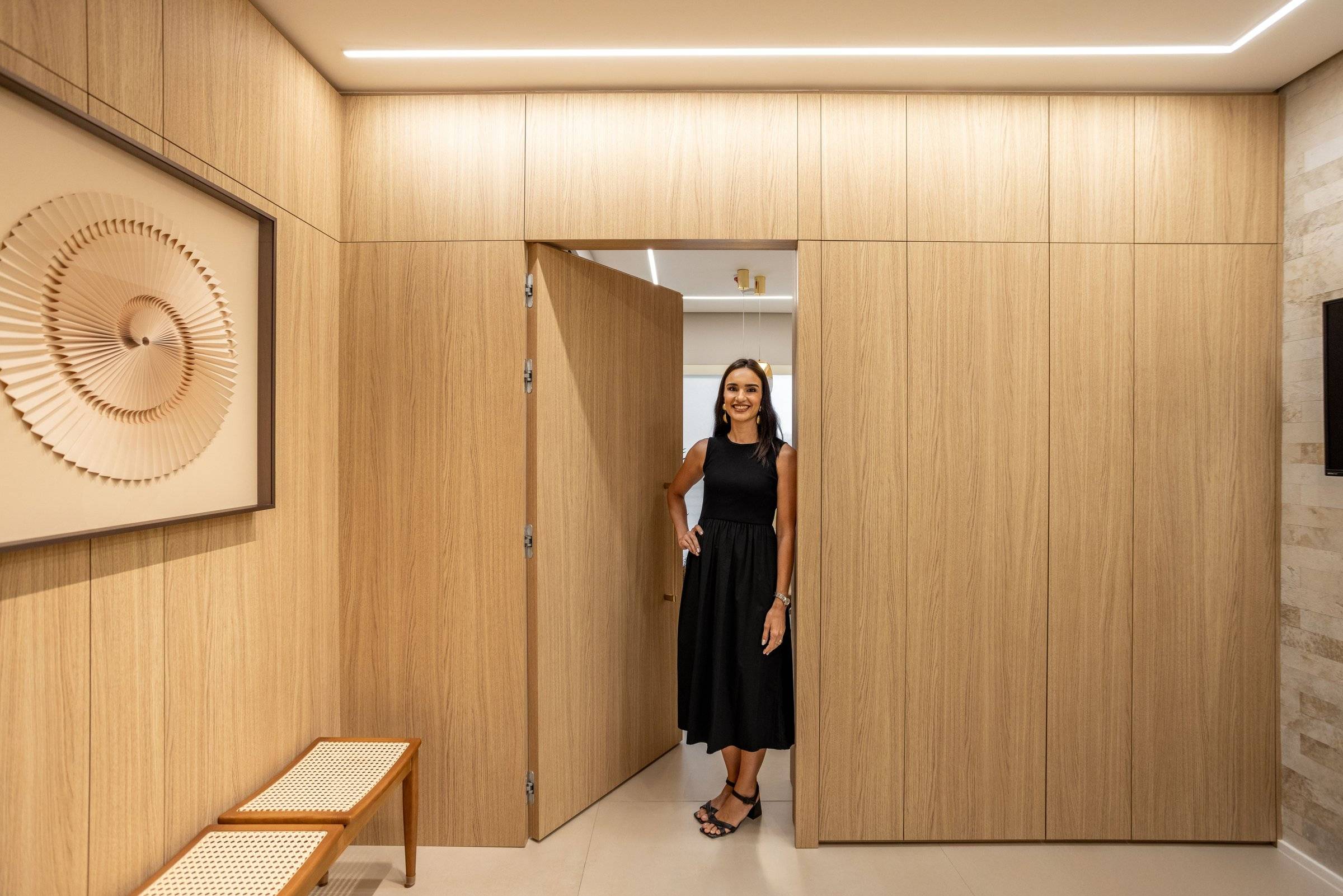 Isabella Porto abrindo a porta embutida no painel de carvalho